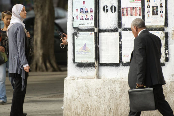 A Tunisian woman in Tunis looks at posters presenting political candidates, on Oct. 20. Some Tunisians fear that if popular Islamist parties take power, they will seek to put their stamp on this moderate, secular state.