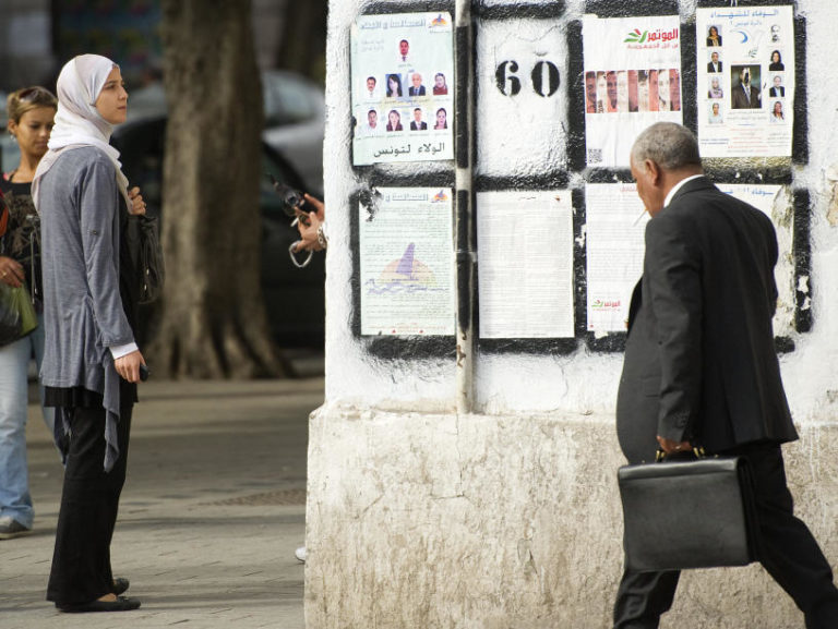 A Tunisian woman in Tunis looks at posters presenting political candidates, on Oct. 20. Some Tunisians fear that if popular Islamist parties take power, they will seek to put their stamp on this moderate, secular state.